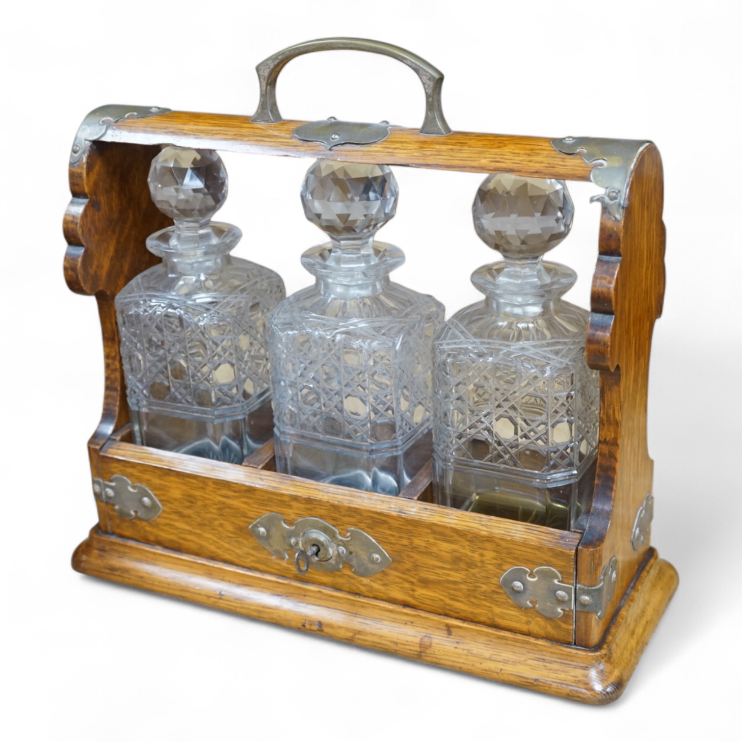 A late Victorian oak tantalus, fitted three square hobnail cut glass decanters, 34cm high. Condition - good